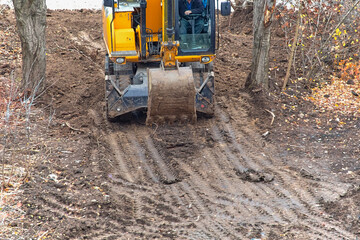 The excavator is performing final soil leveling before the start of construction. The excavator is preparing the site for concrete pouring.