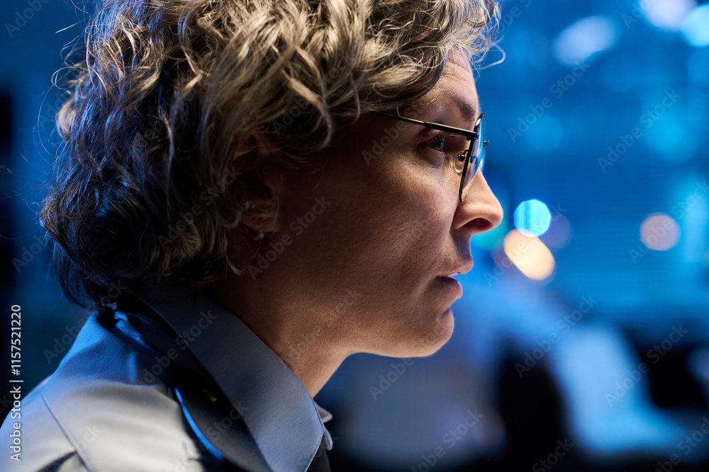 Poster profile of grey haired mature female officer in eyeglasses looking at computer screen with data in f