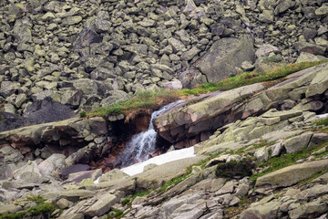 Waterfall among boulders in remote mountains.