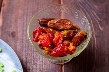 Dogwood, dried dates large sweet in glass container on wooden table