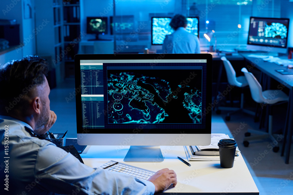 Aufkleber Pensive mature man clicking mouse and looking at screen of desktop computer with graphic data while sitting by workplace