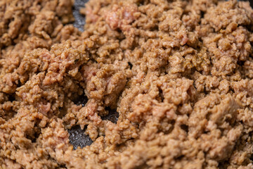 Frozen ground beef is fried with spices in a frying pan with vegetable oil