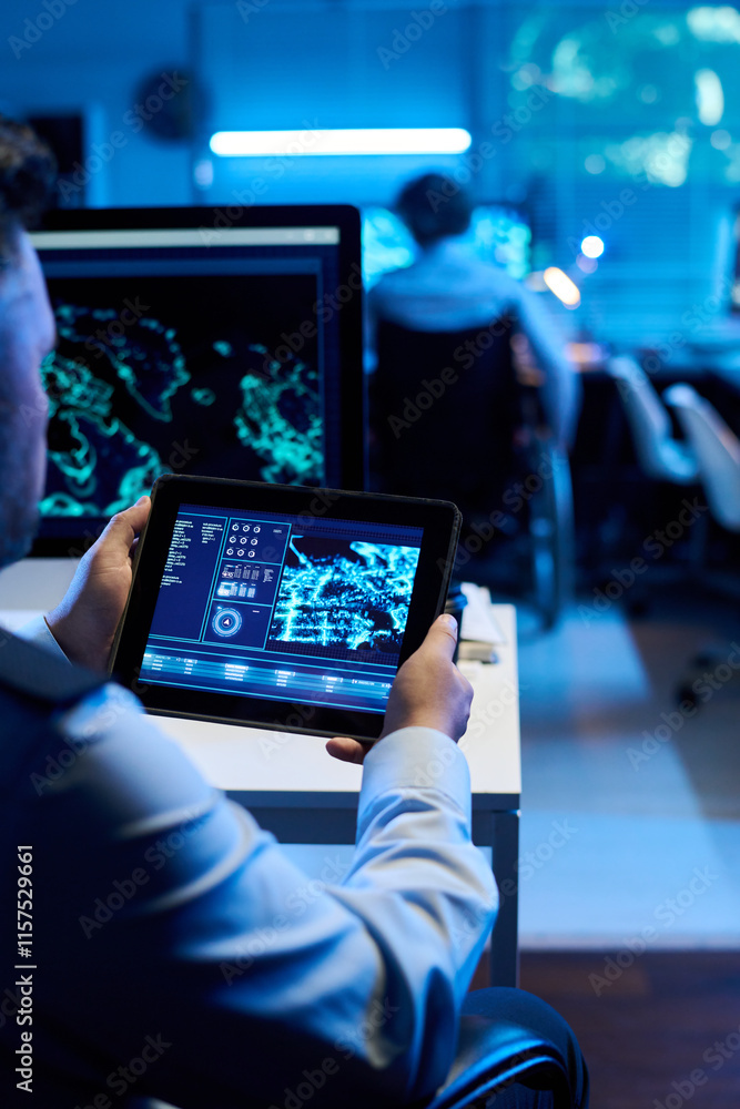Aufkleber Male officer holding digital tablet with graphic data on screen while sitting by workplace and analyzing military location