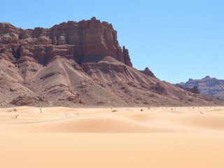 Naklejka premium Majestic Desert Landscape with Red Rock Formations and Golden Sand Dunes Under a Clear Blue Sky in Arid Environment Ideal for Travel and Nature Photography