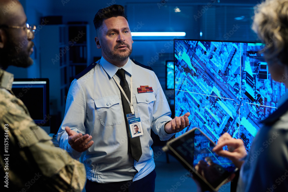 Poster Confident man in uniform standing in front of two intercultural colleagues during discussion of army location on interactive screen