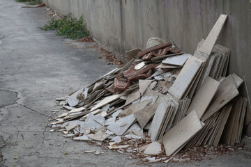 The image shows a pile of construction debris leaning against a concrete wall. 