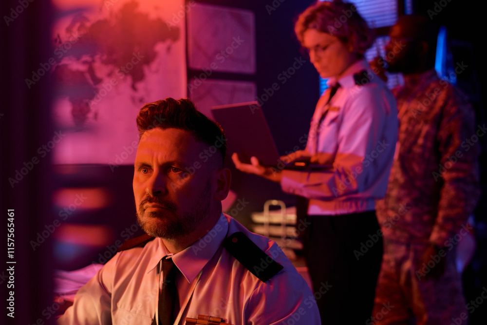 Poster mature male worker of military command center looking at computer screen while analyzing online data