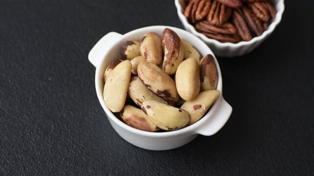 Delicious nutritious brazil nuts in ceramic bowl on dark concrete background