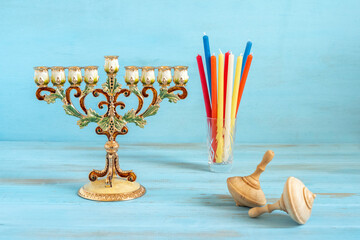 Wooden spinning tops, Hanukkah Menorah, candles for Jewish holiday on blue wooden background.
