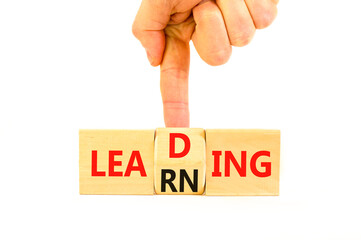 Learning or leading symbol. Concept words Learning Leading on wooden block. Beautiful white table white background. Businessman hand. Business learning or leading concept. Copy space.