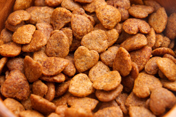Cat crispy treats in heart shapes with brown crunchy texture in rustic wooden bowl. Pet food. Close up. Top view