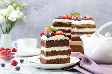 Piece of delicious chocolate sponge cake with berries served on white table