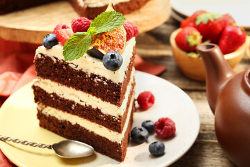 Piece of delicious chocolate sponge cake with berries served on wooden table, closeup
