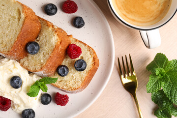 Pieces of freshly baked sponge cake, berries, ice cream, mint and coffee on wooden table, flat lay