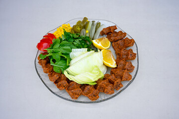 Cig kofte (raw meatball) with lettuce, tomato, pickle and lemon, hot Chee kofta. Turkish local raw food concept.Table scene of assorted take out or delivery foods. Doritoslu duble cig kofte durum.