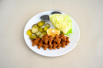 Cig kofte (raw meatball) with lettuce, tomato, pickle and lemon, hot Chee kofta. Turkish local raw food concept.Table scene of assorted take out or delivery foods. Doritoslu duble cig kofte durum.