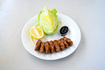 Cig kofte (raw meatball) with lettuce, tomato, pickle and lemon, hot Chee kofta. Turkish local raw food concept.Table scene of assorted take out or delivery foods. Doritoslu duble cig kofte durum.
