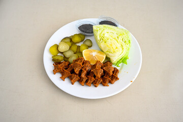 Cig kofte (raw meatball) with lettuce, tomato, pickle and lemon, hot Chee kofta. Turkish local raw food concept.Table scene of assorted take out or delivery foods. Doritoslu duble cig kofte durum.