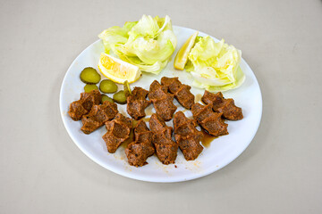 Cig kofte (raw meatball) with lettuce, tomato, pickle and lemon, hot Chee kofta. Turkish local raw food concept.Table scene of assorted take out or delivery foods. Doritoslu duble cig kofte durum.