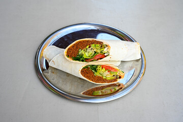 Cig kofte (raw meatball) with lettuce, tomato, pickle and lemon, hot Chee kofta. Turkish local raw food concept.Table scene of assorted take out or delivery foods. Doritoslu duble cig kofte durum.