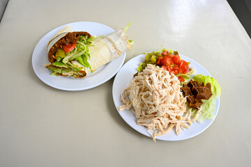 Cig kofte (raw meatball) with lettuce, tomato, pickle and lemon, hot Chee kofta. Turkish local raw food concept.Table scene of assorted take out or delivery foods. Doritoslu duble cig kofte durum.