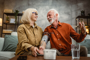 senior wife support and help her senior husband to measure blood pressure