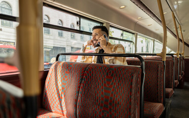 Young man talking on phone while traveling by bus in london © PintoArt