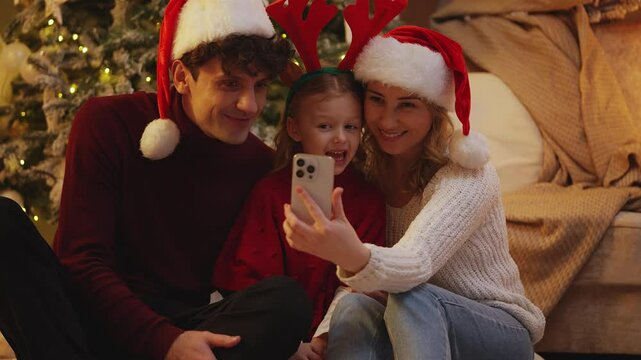 Happy child and her parents make a video call, wishing a merry Christmas