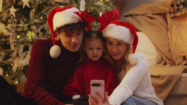 Parents and their little daughter greet loved ones via video call on Christmas