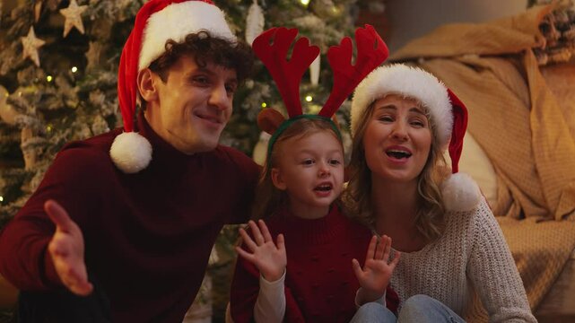 Parents and their child in party hats wish Merry Christmas and a Happy New Year