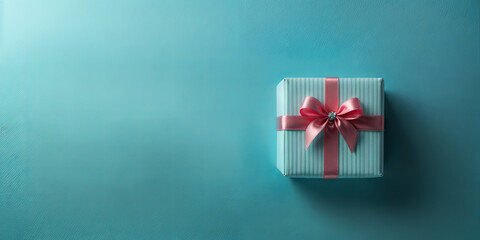 A neatly wrapped gift box sits on a blue surface, featuring a striped design and topped with a pink satin ribbon. This arrangement signifies celebration and joy