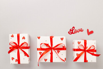 Gift boxes with red hearts on color background, top view