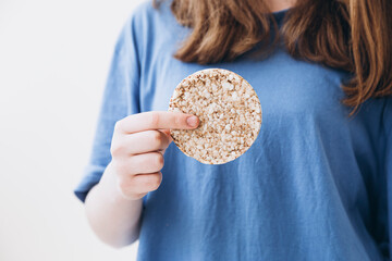 Whole grain cake, buckwheat cake, rice cake in the hands of a girl.