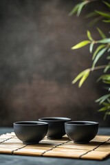 Three elegant black bowls filled with tea arranged on a bamboo mat