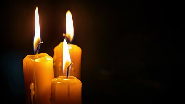 close up of burning candles on the dark background with copy space
