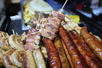 Grilled traditional sausage and different tipe of meat prepared on grill at a Christmas market where various traditional dishes are served.