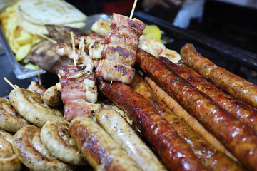 Grilled traditional sausage and different tipe of meat prepared on grill at a Christmas market where various traditional dishes are served.
