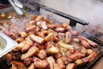 Grilled traditional sausage and different tipe of meat prepared on grill at a Christmas market where various traditional dishes are served.