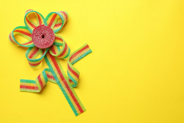 Flower made of tasty sour belts on yellow background, top view. Space for text