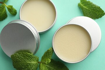 Natural lip balms and mint leaves on turquoise background, flat lay
