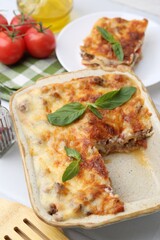 Delicious cooked lasagna with basil on white table, closeup