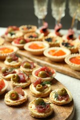 Many different tasty canapes and wine on white table, closeup