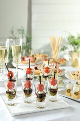 Many different tasty canapes and wine on white table