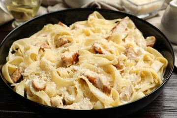 Tasty Alfredo pasta with chicken on wooden table, closeup