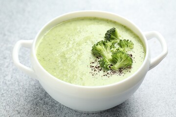 Delicious broccoli cream soup in bowl on light table, closeup