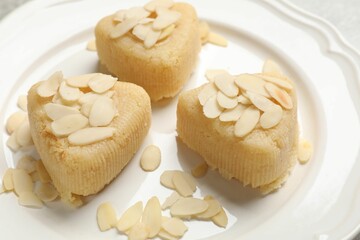 Pieces of delicious sweet semolina halva with almond flakes on plate, closeup