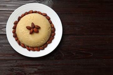 Delicious semolina halva with almonds on wooden table, top view. Space for text