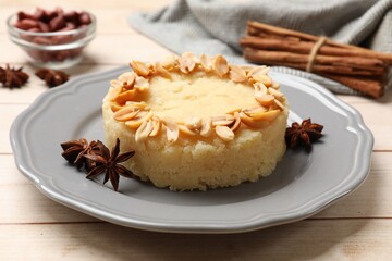 Delicious semolina halva with almond flakes and spices on white wooden table, closeup
