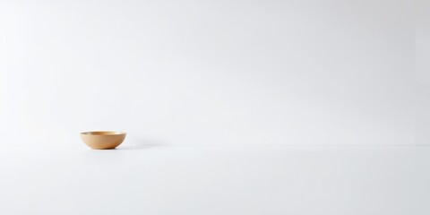 A simple beige bowl sits on a plain white surface against a stark white background