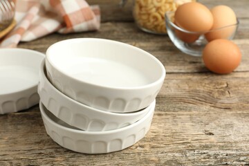 Ceramic casseroles and eggs on wooden table, closeup